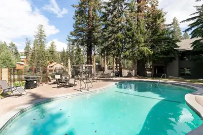 a swimming pool in a yard with chairs and trees at Seasons Four 193 in Mammoth Lakes