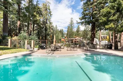 a swimming pool with chairs and tables and trees at Seasons Four 193 in Mammoth Lakes