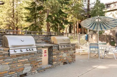 an outdoor grill with an umbrella and a table and chairs at Summit 43 in Mammoth Lakes