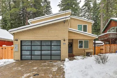a house with a garage door in the snow at Tahoe Toasty - 3 Bedroom Home Near Sledding Hill in South Lake Tahoe