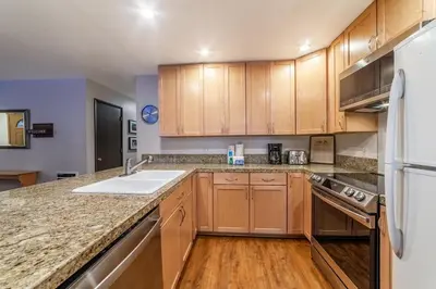 a kitchen with wooden cabinets and a white refrigerator at Adventure by Day Cozy Nights Family Alpine Condo in Mammoth Lakes