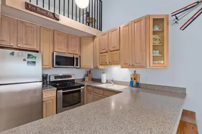a kitchen with wooden cabinets and stainless steel appliances at Stylish Mammoth 1BR & Loft With Fireplace in Mammoth Lakes