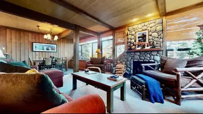 a living room filled with furniture and a stone wall at Treehouse at Canyon Lodge Walk to Slopes in Mammoth Lakes