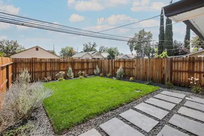 a backyard with a wooden fence and a green lawn at Pet-Friendly Private Cottage In Tahoe Park in Sacramento
