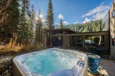 a hot tub in front of a house at Painted River Retreat by Tahoe Getaways - 4BR w River Views, Hot Tub & EV Charger. in Truckee