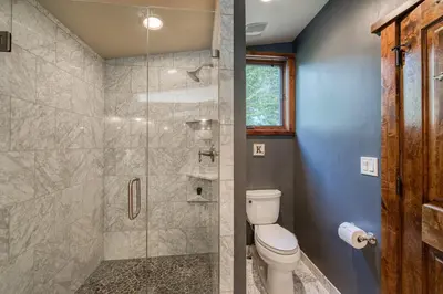 a bathroom with a toilet and a glass shower at Painted River Retreat by Tahoe Getaways - 4BR w River Views, Hot Tub & EV Charger. in Truckee