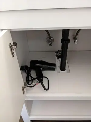 a shelf with a hair dryer under a sink at 721 Cozy Mid-Town Hideaway in Reno