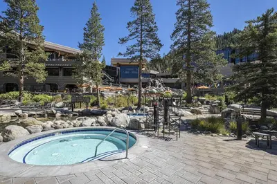 a swimming pool in a garden with rocks and a building at Walk to Palisades Tahoe Ski Lifts Mtn-View Condo in Olympic Valley