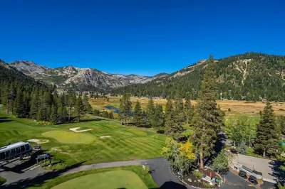 an aerial view of a golf course with mountains at Sweeping Views and Access to Slopes Everline Condo in Olympic Valley