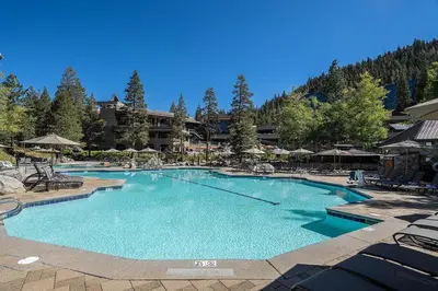 a large swimming pool with chairs and umbrellas at a resort at Valley Vistas, Resort Perks Everline Studio Condo in Olympic Valley