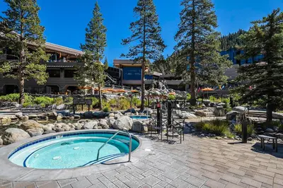 a swimming pool in a garden with a building in the background at Valley Vistas, Resort Perks Everline Studio Condo in Olympic Valley