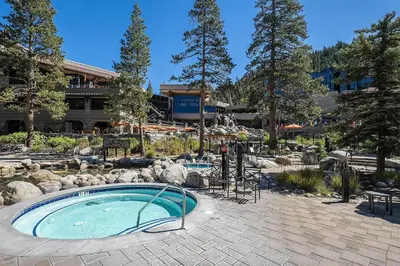a swimming pool in a garden with a building and trees at Valley Vistas, Resort Perks Everline Studio Condo in Olympic Valley