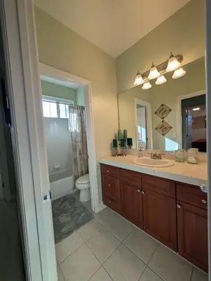 a bathroom with a sink and a toilet and a mirror at Spacious 5-bedroom 3-bath house in NW Fresno in Fresno