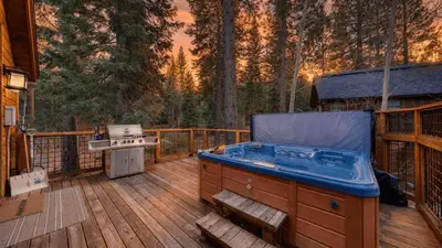a hot tub on a wooden deck with a grill at Truckee Mountain Cabin with Hot Tub Game Room Forest Views Gray Wolf Lodge by AvantStay in Truckee