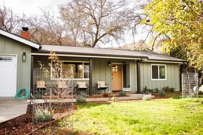 a green house with a porch and a yard at Quiet retreat - Hot tub & sauna in Three Rivers in Three Rivers