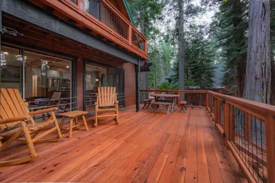 a wooden deck with chairs and a table on it at Whispering Pines Cabin For 6 in Carnelian Bay