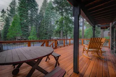 a wooden deck with a table and a chair on it at Whispering Pines Cabin For 6 in Carnelian Bay
