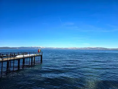a person standing on a pier in the water at Chamberland retreat-Hot Tub, Pool Table, Movie & Ski in Homewood