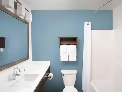 a bathroom with a white toilet and a blue wall at WoodSpring Suites Manteca - Stockton South in Manteca