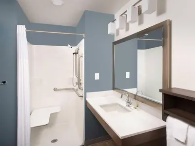 a bathroom with a sink and a mirror at WoodSpring Suites Manteca - Stockton South in Manteca