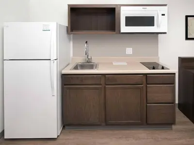 a kitchen with a white refrigerator and a sink at WoodSpring Suites Manteca - Stockton South in Manteca