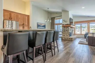a kitchen and living room with a bar with black chairs at Snowcreek 704 in Mammoth Lakes