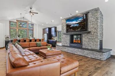 a living room with a couch and a stone fireplace at Paradise on Pioneer - New 6 Bedroom w Pool Table in South Lake Tahoe
