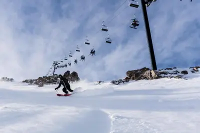 a person riding a snowboard down a snow covered slope with a ski lift at Timberline #08 condo in Mammoth Lakes
