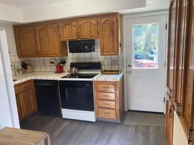 a kitchen with wooden cabinets and a black and white appliance at Sunset Cottage near Yosemite in Oakhurst