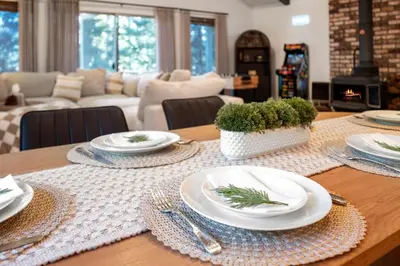 a wooden table with plates and utensils on it at Modern Cabin Escape wGame Room, Huge Deck, WIFI in Arnold