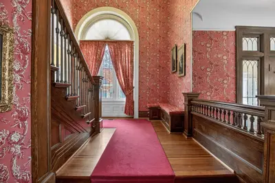 an ornate hallway with stairs and red wallpaper at The Spalding House Comfort in Visalia home in Visalia