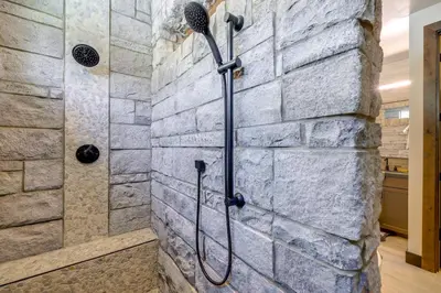 a bathroom with a stone wall and a shower at Steps From Sledding Hill! Soda Springs Mtn Retreat in Soda Springs
