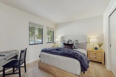 a bedroom with a bed and a desk and windows at Spectacular Lake Views in Tahoe City