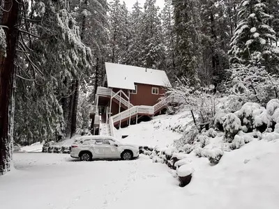 a car parked in front of a house covered in snow at El Capitan Hideaway - A-Frame Cabin Yosemite West in Yosemite West