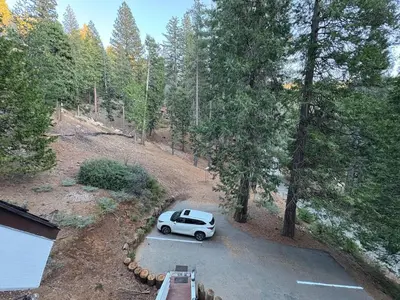 a car parked in a parking lot in the woods at El Capitan Hideaway - A-Frame Cabin Yosemite West in Yosemite West