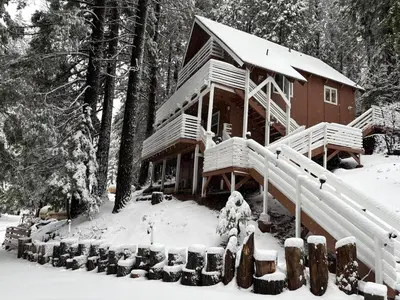 a log cabin with snow on the front of it at El Capitan Hideaway - A-Frame Cabin Yosemite West in Yosemite West