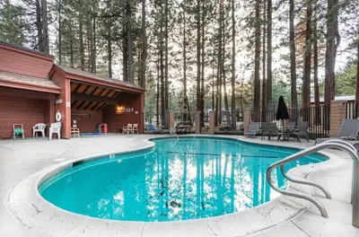 a swimming pool in front of a house with trees at Winterset 4 in Mammoth Lakes