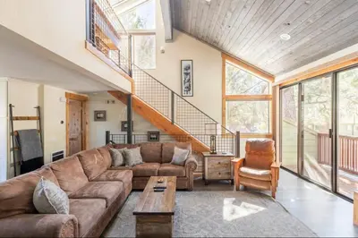 a living room with a brown couch and a staircase at Mammoth Sierra Townhome 1 in Mammoth Lakes