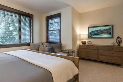 a bedroom with a bed and a dresser and windows at Timbers 1057 in Mammoth Lakes