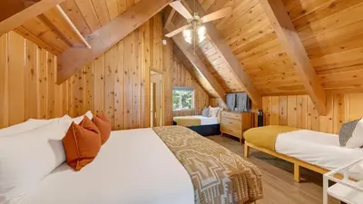 a log cabin bedroom with a bed and a tv at Hot Tub • Firepit • Loft Suite Mins to World-Class Skiing Tahoe A-Frame Retreat by AvantStay in Carnelian Bay