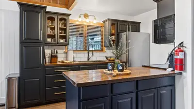 a kitchen with black cabinets and a refrigerator at Hot Tub • Firepit • Loft Suite Mins to World-Class Skiing Tahoe A-Frame Retreat by AvantStay in Carnelian Bay