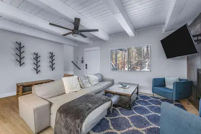 a living room with a couch and a flat screen tv at Zephyr Chalet Steps from Zephyr Cove in Glenbrook