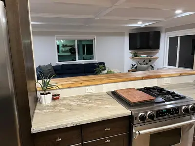 a kitchen with a stove and a couch in the background at Peach lane house in Newcastle