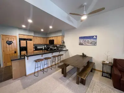 a kitchen with a table and bar with stools at Ski-in Ski-out Family Condo steps from lifts in Kirkwood