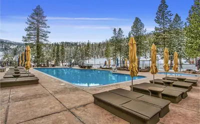 a swimming pool with lounge chairs and umbrellas at Ritz-Carlton Northstar Luxury Ski-In Ski-Out in Truckee