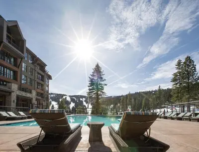 a resort pool with chairs and the sun in the sky at Ritz-Carlton Northstar Luxury Ski-In Ski-Out in Truckee
