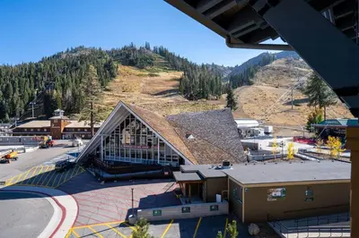 a large building with a mountain in the background at Top Floor Village Ski-In/Ski-Out Condo in Olympic Valley