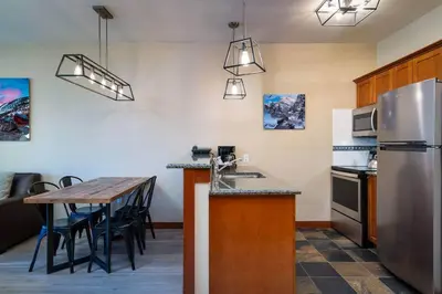 a kitchen with a table and a stainless steel refrigerator at Top Floor Village Ski-In/Ski-Out Condo in Olympic Valley
