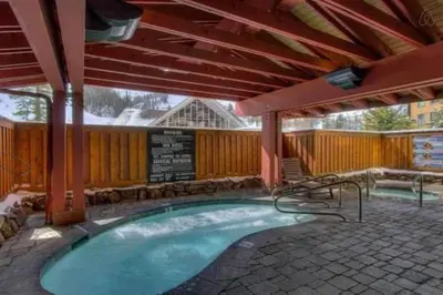 a large swimming pool with an umbrella and a patio at Top Floor Village Ski-In/Ski-Out Condo in Olympic Valley