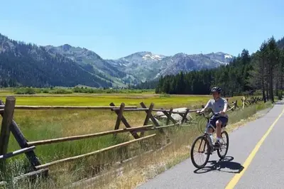 a man riding a bike down a road at 3BR Condo in Village at Palisades - Premier in Olympic Valley